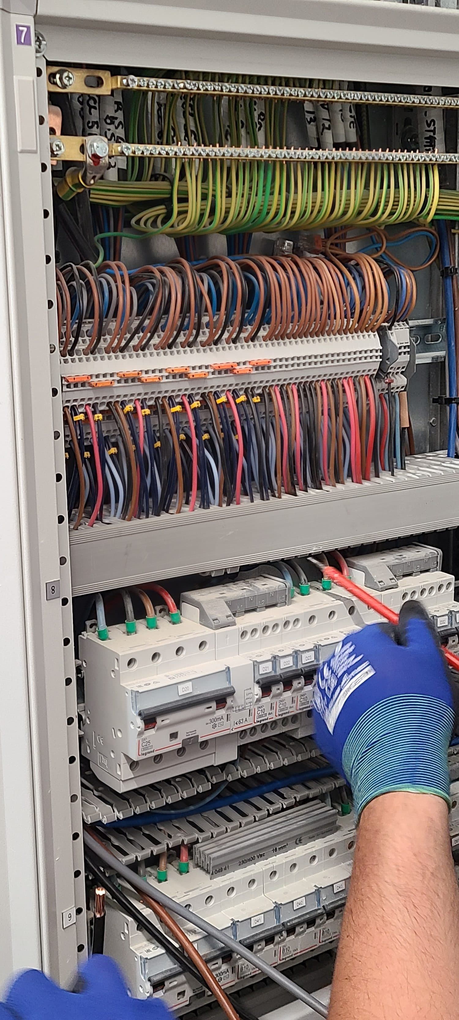 Câblage d’une armoire de sous-station de comptage, main gantée, fils de couleur
